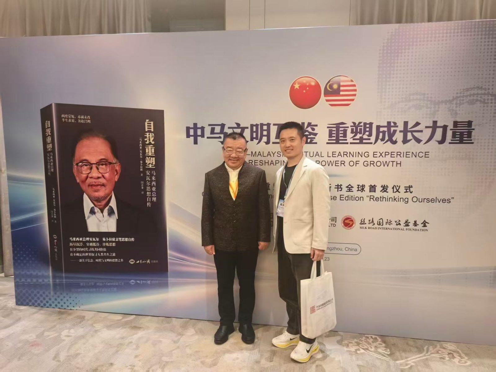 虎翼智贸创始人与中国丝路集团董事长阎立金在活动主题背景板前留影